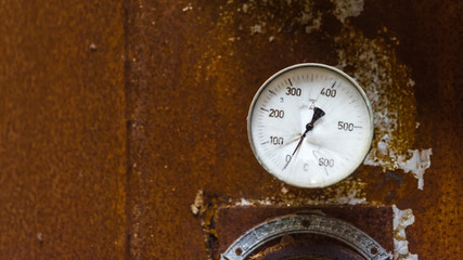 The old broken temperature gauge with rusty background