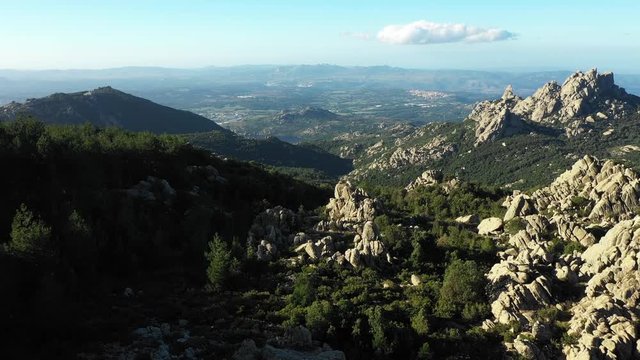 Video from above, aerial view of a beautiful valley surrounded by granite mountains and green vegetation, Monte Limbara, Sardinia, Italy.