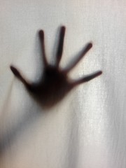 Shadow hand behind the curtain.Blurred hand abstraction. Halloween background in black and white tone picture style