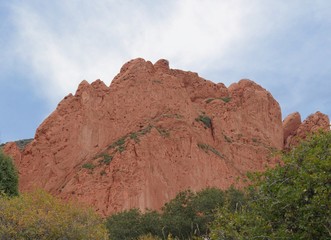 Scenic rock wall with green and yellow trees at the Garden of the Gods, a National natural landmark in Colorado Springs, Colorado.
