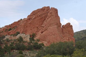 Fototapeta premium Beautiful rock wall formation with trees and bushes at the Garden of the Gods, a National natural landmark in Colorado Springs, Colorado.