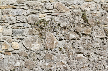 Antique 19th century European stone wall background with stones of varying shapes and sizes, in light gray and brown colors