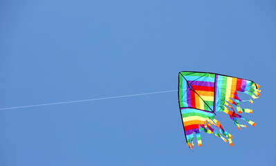 multicolored kite flyies on the blue sky