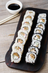 Japanese restaurant menu photo, traditional cuisine, delicious seafood, food art.  Appetizing maki sushi rolls with sauce and chopsticks