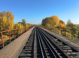 Obraz premium Railway bridge over the river under the blue sky in autumn