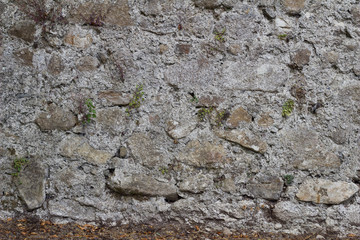 Antique 19th century European stone wall background with stones of varying shapes and sizes, in light gray and brown colors