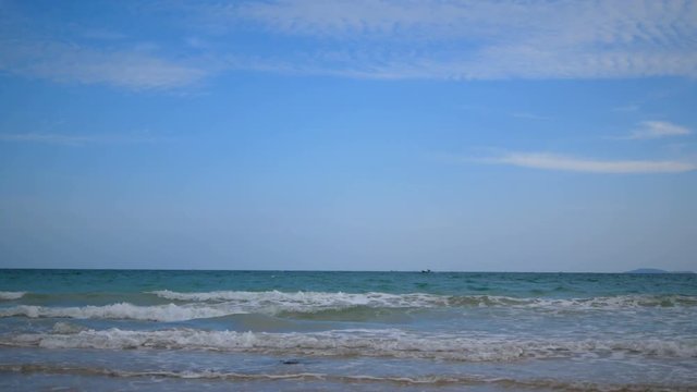 A fishing boat sailing on the sea with beautiful blue sky and waves at the beach