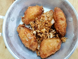 Top view of fried chicken wings with fried garlic on plate