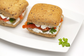 Sandwich with salmon, cheese and cereal bread on white background. Close up.