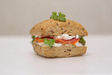 Sandwich with salmon, cheese and cereal bread on white background. Close up.