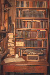 an old typewriter is on the table.writer's room.old books are on the shelves.Vintage room of the researcher, critic, scientist,