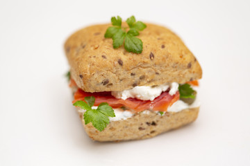 Sandwich with salmon, cheese and cereal bread on white background. Close up.