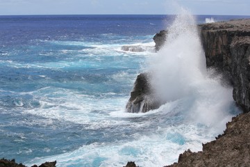 Obraz premium Forceful giant waves smash against the steep cliffs of the As Matmos Fishing Cliff on Rota, Northern Mariana Islands