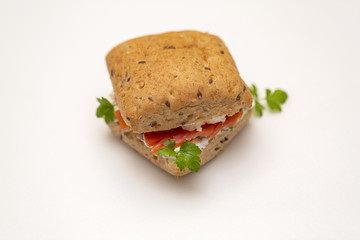Sandwich with salmon, cheese and cereal bread on white background. Close up.