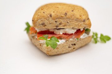 Sandwich with salmon, cheese and cereal bread on white background. Close up.