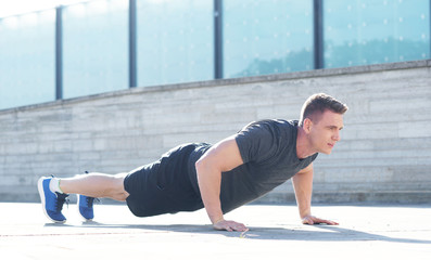 Young and sporty man training outdoor in sportswear. Sport, health, urban athletics.