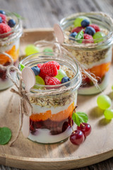 Sweet granola with fresh fruits and yoghurt in jar