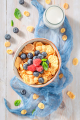 Tasty cornflakes with berry fruits and milk on rustic table