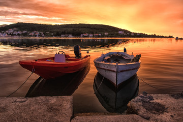 Zwei beieinander liegende Boote im Farbspiel des Sonnenuntergangs