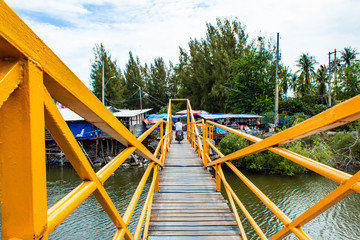 A wooden bridge over the canal The steel building painted yellow cattle.