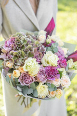Young girl holding a beautiful spring bouquet. flower arrangement with hydrangea and garden roses. Bright dawn or sunset sun