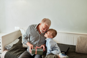 Grandson is giving present to his grandfather in living room