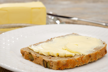 Eine Scheibe Butterbrot und ganze Butter im Hintergrund