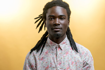 young handsome afro american man with dreadlocks isolated on yellow background