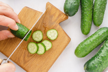 Mans hands cutting cucumbers for detox water. Top view. Process of preparing energy cocktail