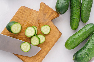 Cutting board with sliced cucumbers for detox water. Top view. Process of preparing energy cocktail