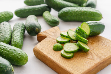 Cutting board with sliced cucumbers for detox water. Process of preparing energy cocktail