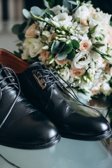 men's shoes and a wedding bouquet on a glass table. Wedding details