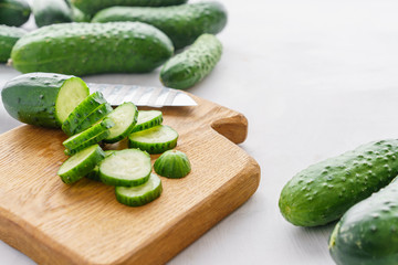 Cutting board with sliced cucumbers for detox water. Process of preparing energy cocktail