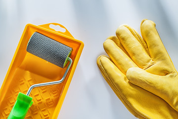 Yellow safety gloves paint tray roller on white surface
