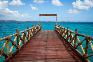 Obraz premium Lovely wooden pier leading to turquoise Indian Ocean at Prison Island near Zanzibar, Tanzania. Romantic and inspiration view on a sunny and lovely day