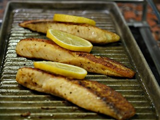 Grilled fish fillet still hot on the griller with slices of lemon on top