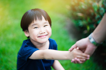 Asia boy is smiling happily. Shaking hands with his father in the garden Show love, caring for the family. Make children feel warm and have a good mind.