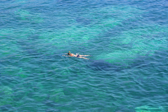 aerial view of swimming girl in the blue sea 