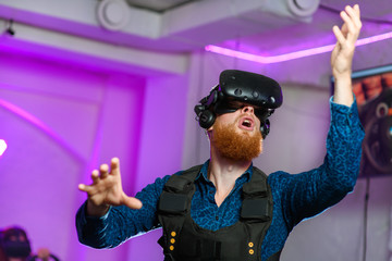 A young guy, with a red beard, is playing virtual reality games