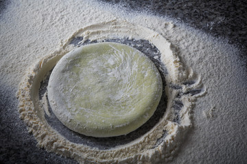 piece of dough for pizza in flour