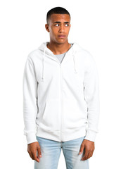 Fototapeta premium Dark-skinned young man with white sweatshirt is a little bit nervous and scared pressing the teeth on isolated white background