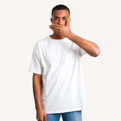 Young african american man covering mouth with hands for saying something inappropriate. Can not speak on isolated background