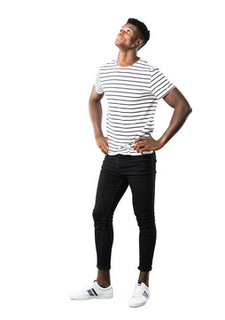 Full body of Dark skinned man with striped shirt standing and looking to the side on white background