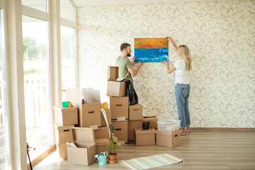 young couple hanging picture on wall together while moving into new home