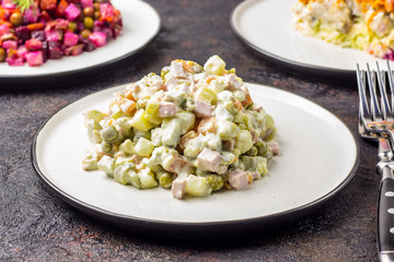 Russian food on dark background. Assortment salad of Russian cuisine - Olivier salad, vinaigrette - beet salad, herring salad. Top view. Copy space.