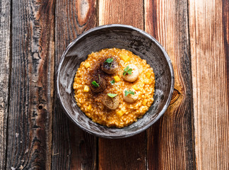 Pumpkin risotto with scallops in a bowl, wooden background, copy space.