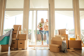 Happy young Couple Carrying Cardboard Boxes Into New Home On Moving Day