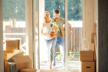 Smiling couple hold boxes in new home. Dreaming new home