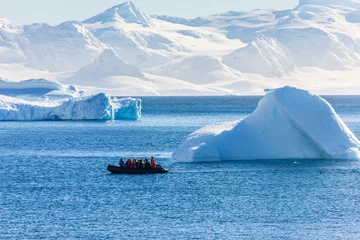 Rolgordijnen Boot vol toeristen langs de enorme ijsbergen in de baai bij het eiland Cuverville, Antarctisch schiereiland © vadim.nefedov