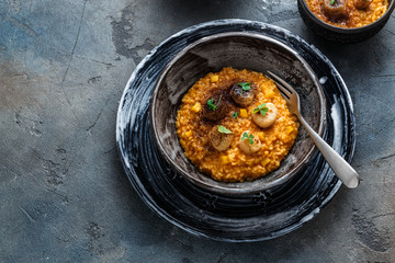 Risotto with pumpkin and scallops, on stone background, copy space